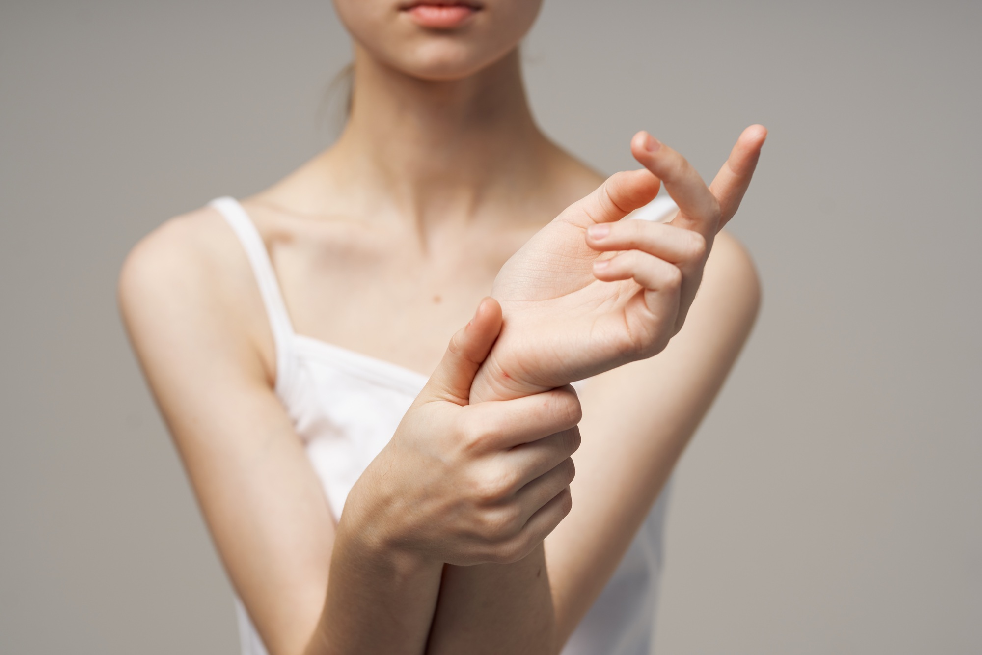 woman in white t-shirt holding on to the arm health problems joint studio treatment
